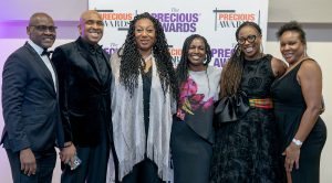 Guests pose for a photo in front of the PRECIOUS Awards logo.